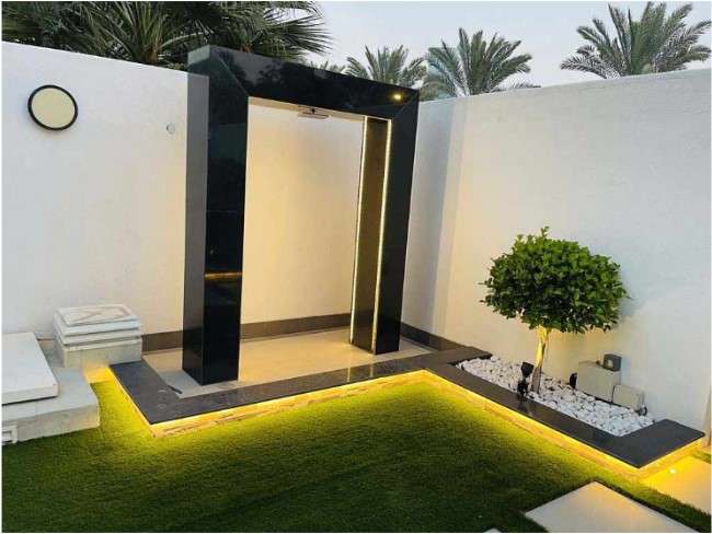 Experience a unique bathroom ambiance with a black door and a touch of green grass, meticulously designed and installed by experienced landscaping companies in Dubai. This distinctive space reflects the innovative approach and expertise of Dubai's top landscaping professionals.
