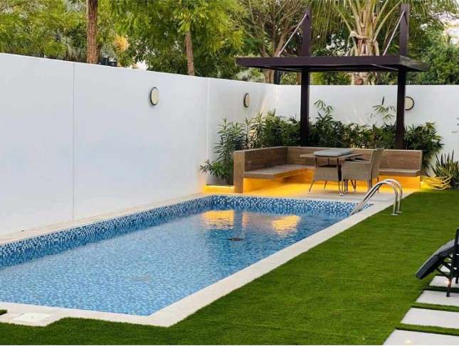 Explore a small but inviting Dubai backyard featuring a swimming pool and lawn chairs, calling for swimming pool maintenance. When seeking expertise, consider top landscaping companies in Dubai to ensure the optimal care and enhancement of your outdoor space.