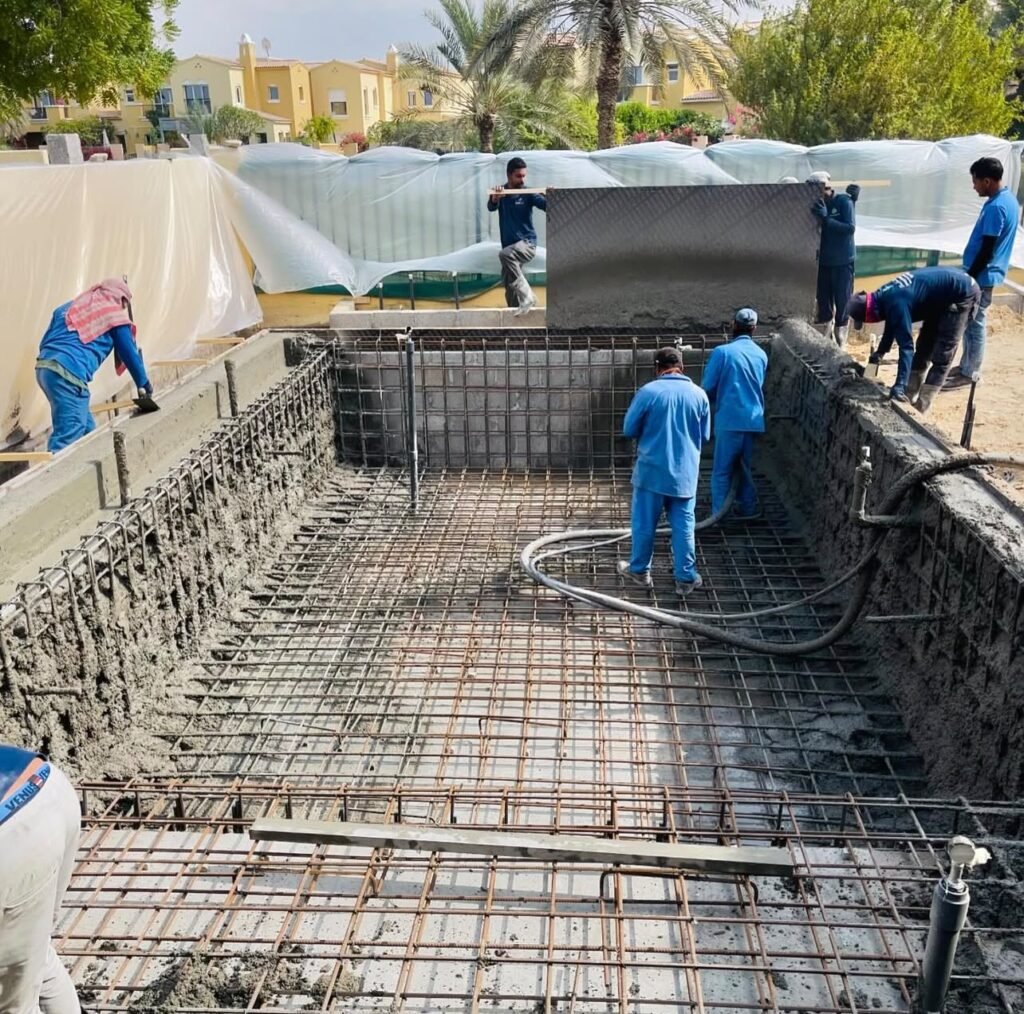 Swimming pool construction in progress, showing steel reinforcement across the base and walls while the team works on the pool shell.