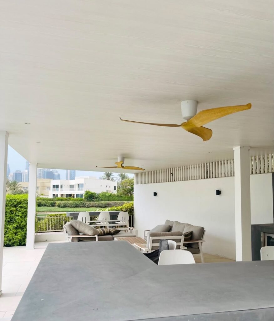 A covered outdoor living area with a fitted counter, ceiling fans and space for sheltered seating and dining.