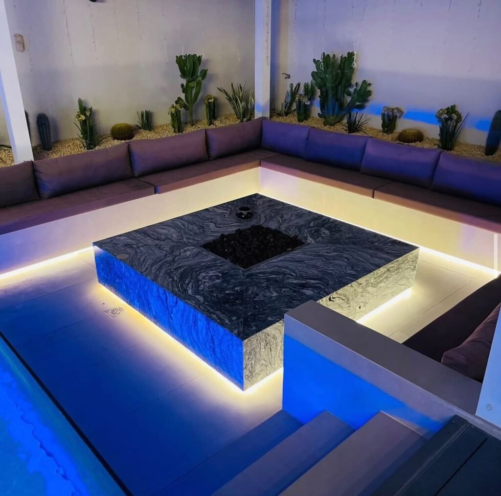 A sunken outdoor seating area with cushioned benches, a central table and concealed lighting beneath the seating.